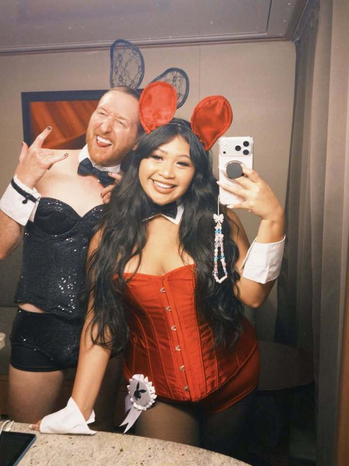 A man and a woman in "Playboy Bunny" costumes. The woman is taking a mirror selfie.