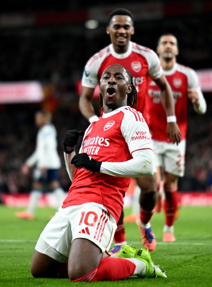Arsenal player Albert Sambi Lokonga celebrates a goal, kneeling on the grass with his mouth open.