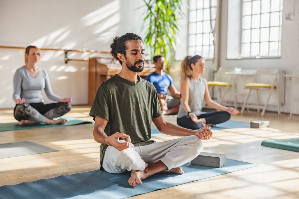 Man meditating in a yoga class with other people.