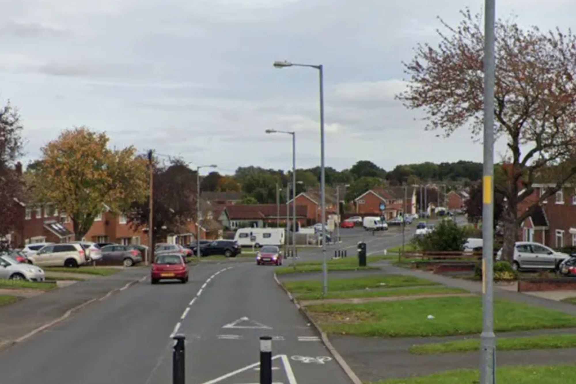 An image collage containing 1 images, Image 1 shows A street view of a residential area with cars parked on the side of the road and houses in the background