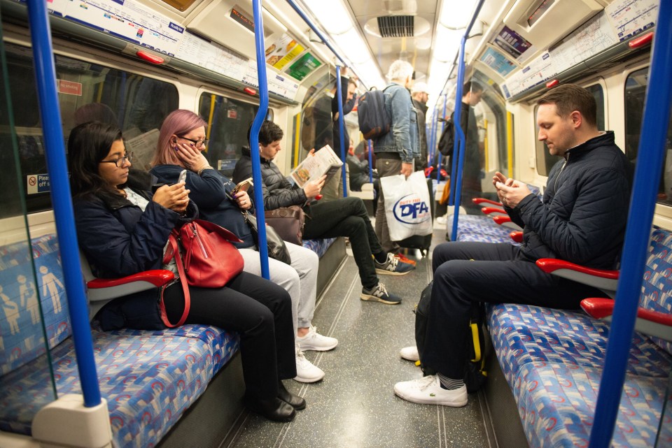 Passengers sitting and standing in a train car.