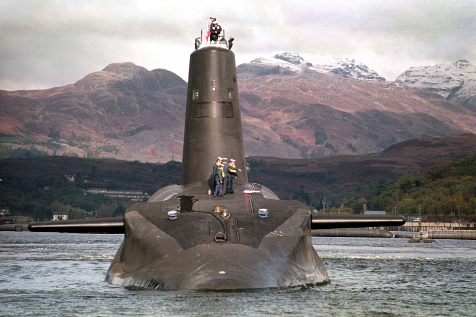 HMS Vanguard, Britain's first Trident nuclear submarine, on the River Clyde, Scotland, with mountains in the background.