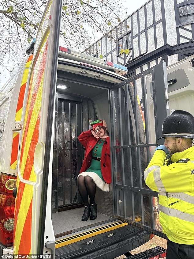 A woman dressed as an elf can be seen in the back of a police van following the protest