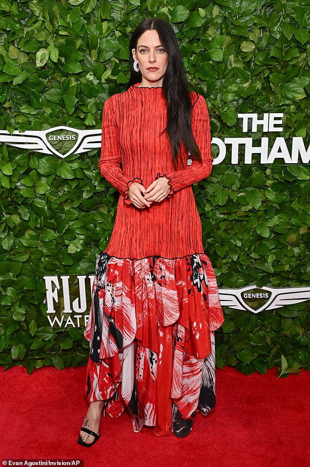Riley Keough went for a patterned, red look as she wore a long-sleeved shift dress with a drop hem skirt with inspired petals with what appeared to be flower imagery on them. The nepo baby actress teamed the busy dress with black, patent leather sandal heels and white, acrylic hoops