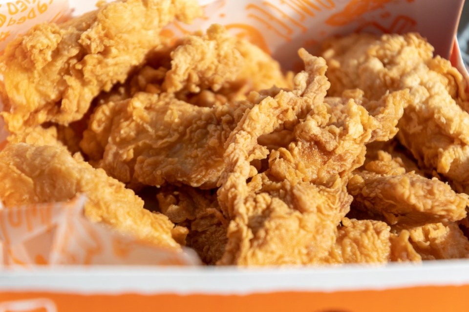 Close-up of Popeyes' crispy fried chicken tenders in a box.