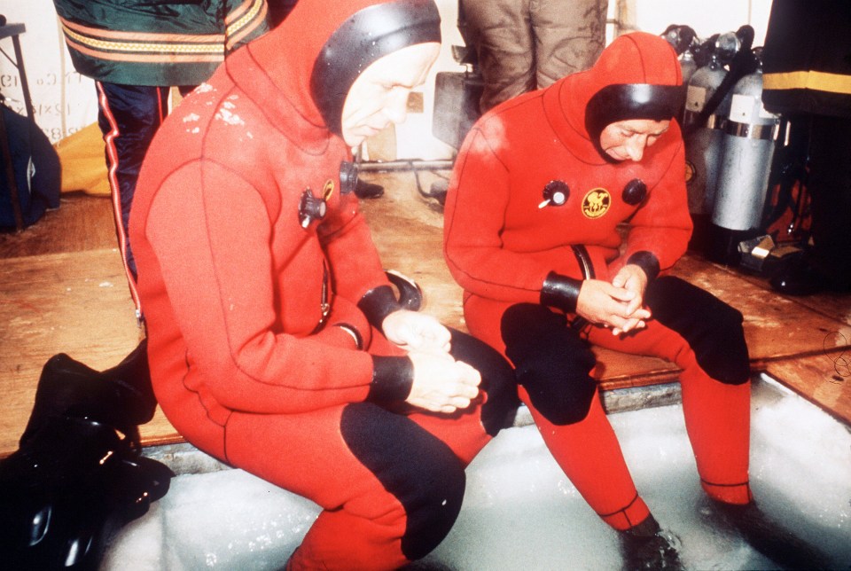 Prince Charles in a red diving suit prepares to walk under arctic ice.