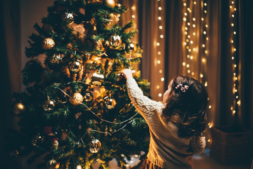 Child decorating a Christmas tree.
