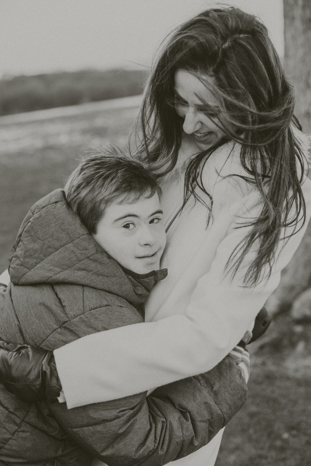 Black and white photo of a woman embracing a boy with Down syndrome.