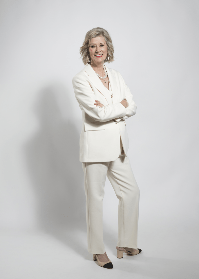 Woman in a white pant suit with arms crossed.