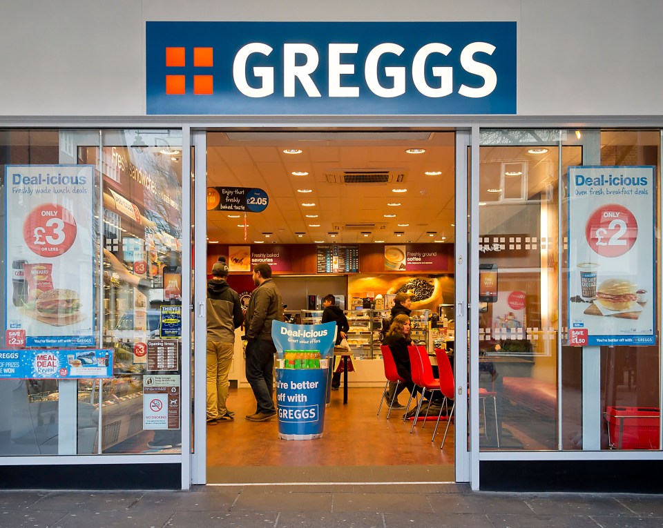 Exterior of a Greggs Bakery in Canterbury, Kent, showing customers inside and promotional posters in the windows.