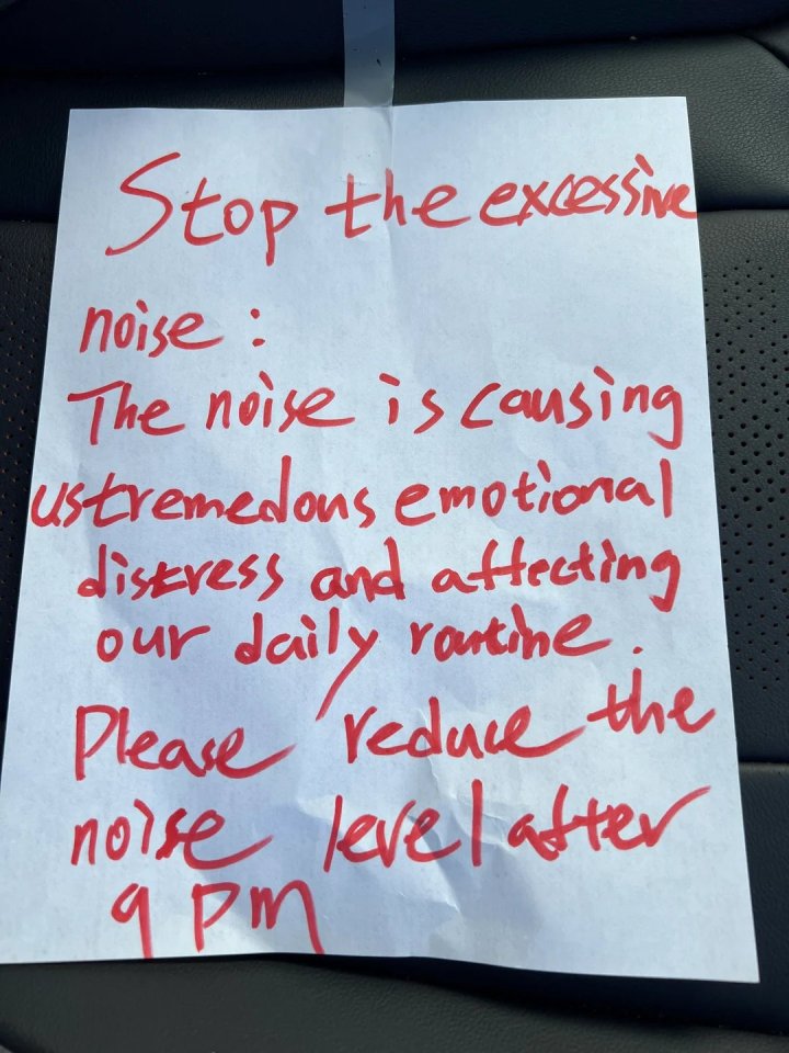 A note written in red ink on white paper reads "Stop the excessive noise: The noise is causing us tremendous emotional distress and affecting our daily routine. Please reduce the noise level after 9 PM."