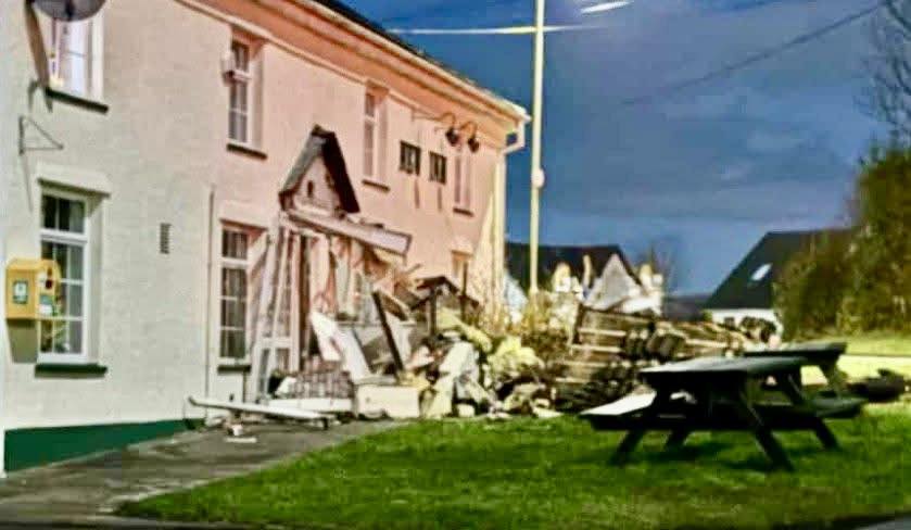 Damage to the front of a white building, possibly a pub, with debris scattered on the ground.