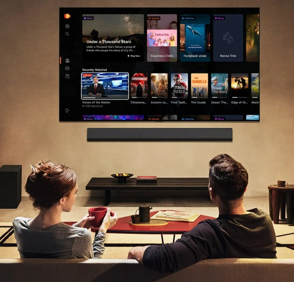 A couple watching LG Channels on a large TV in a modern living room at night.