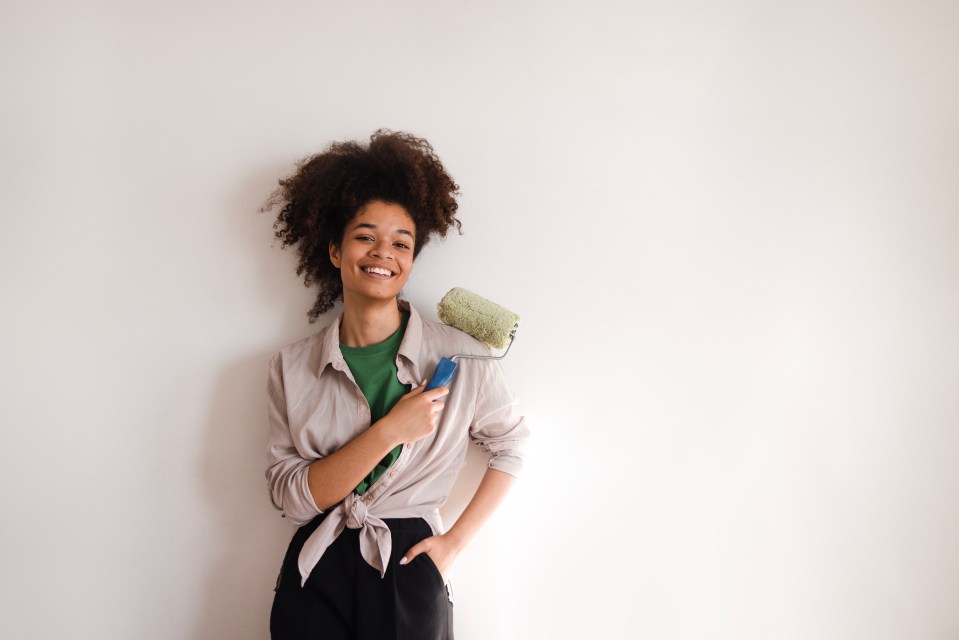 Smiling young African American woman holding a paint roller.