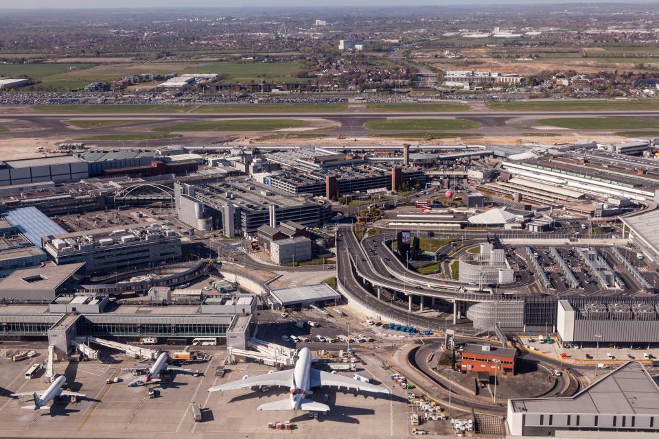 Aerial view of the London Heathrow Airport with planes parked at the gates, runways, and buildings.