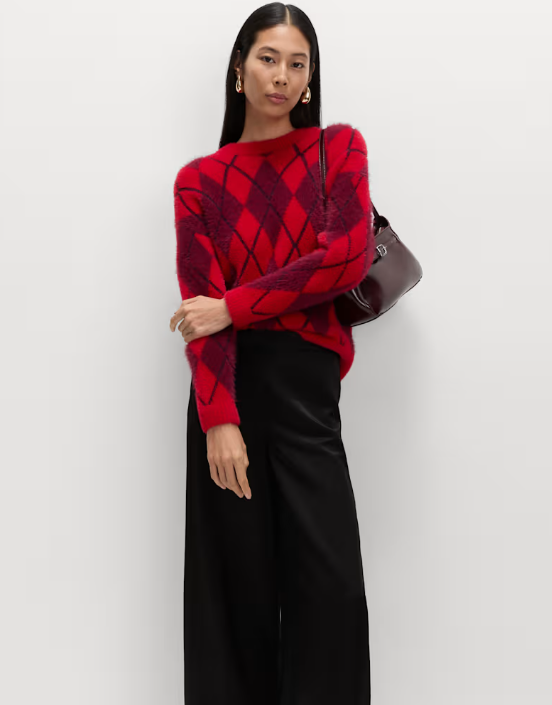 Model wearing a red argyle jumper and black trousers.