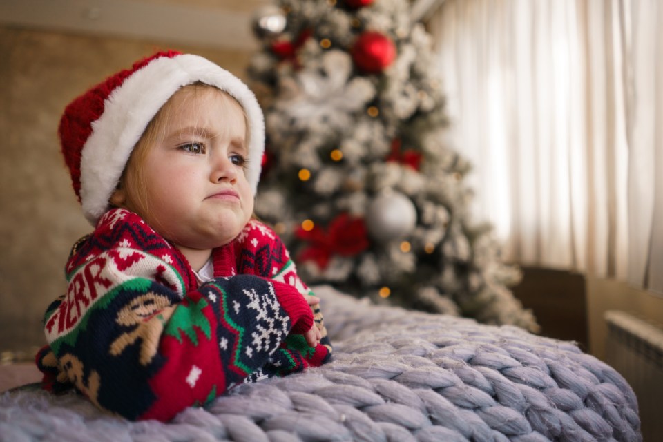 Angry and sad little girl in Christmas clothes.