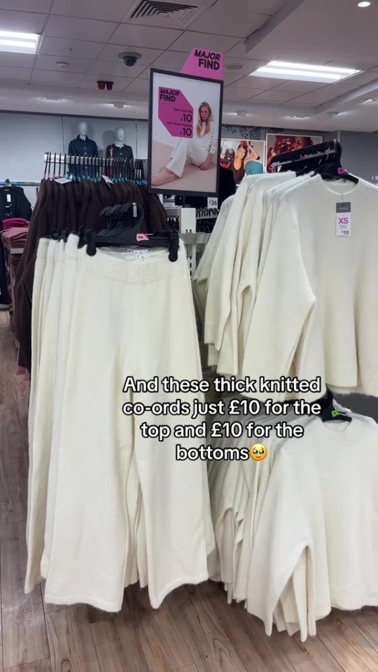 Clothing racks in a store display cream-colored knitted co-ord sets, with a sign in the background advertising a "MAJOR FIND" of "Soft Touch Tops" for £10.