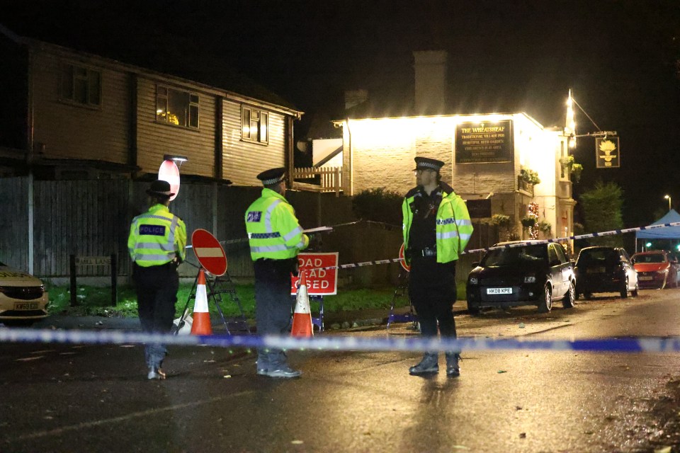 Police officers at a cordoned-off crime scene near The Wheatsheaf pub.