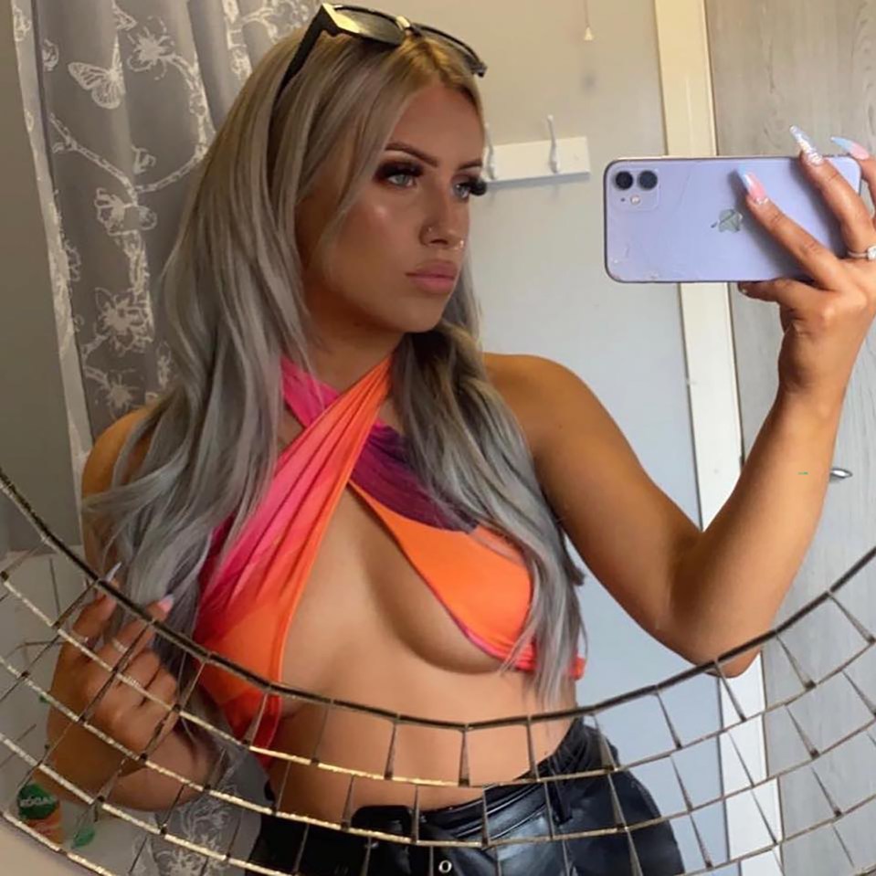 Woman taking a selfie in a revealing orange top.