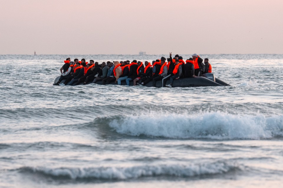 Migrants in an inflatable dinghy preparing to sail into the English Channel.
