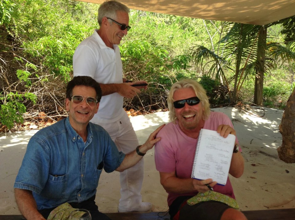 Jeffrey Epstein, Richard Branson, and a third man under a canopy on a beach.