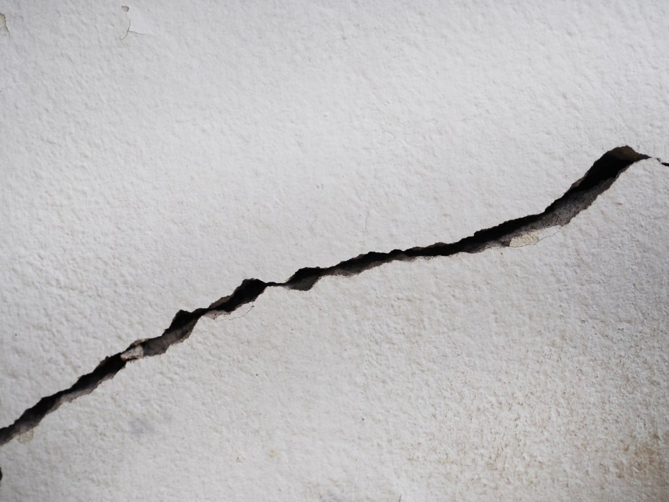 A deep crack in a white cement wall.