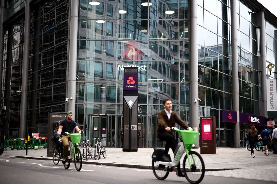 Two cyclists ride past the NatWest bank headquarters in London.