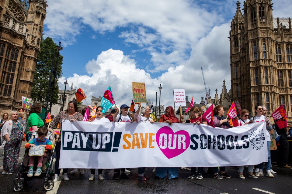 Teachers from the National Education Union march on Parliament with a banner saying "PAY UP! SAVE OUR SCHOOLS."