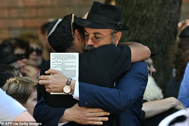Mourners hug after the funeral service for 10-year-old Matilda, who was killed in the December 14 Bondi Beach shooting attack, in Sydney on December 18, 2025. Australia's Prime Minister Anthony Albanese promised a sweeping crackdown on "hate, division and radicalisation" on December 18 after a mass shooting killed 15 people at a Jewish festival on Bondi Beach. (Photo by Saeed KHAN / AFP via Getty Images)