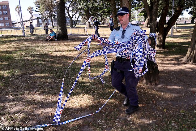 TOPSHOT - Police officers remove police tape from the scene of Sunday's shooting at Bondi Beach, in Sydney on December 17, 2025. Police charged alleged Bondi killer Naveed Akram with terrorism, 15 counts of murder and a litany of other crimes after Australia's worst mass shooting in decades. (Photo by DAVID GRAY / AFP via Getty Images)