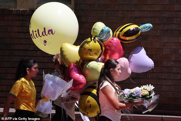 People carry balloons as they arrive for the funeral of 10-year-old Matilda, who was killed in the December 14 Bondi Beach shooting attack, in Sydney on December 18, 2025. The attack at Bondi Beach on December 14 was one of the deadliest in Australian history. (Photo by DAVID GRAY / AFP via Getty Images)