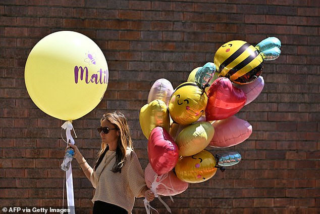 A mourner carries balloons while arriving for the funeral