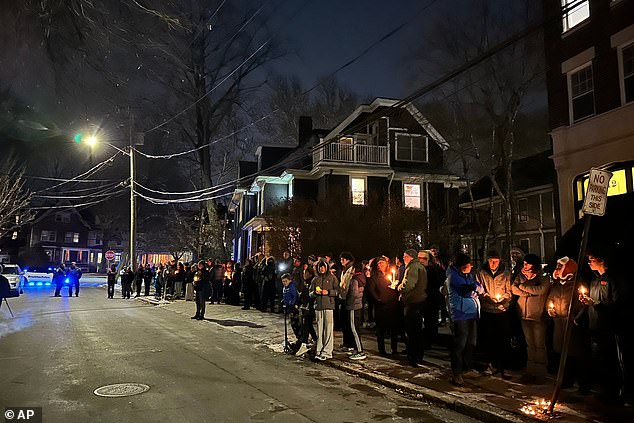 A crowd of people holding candles gather outside the home of Massachusetts Institute of Technology professor Nuno F.G. Loureiro in Brookline, Massachusetts
