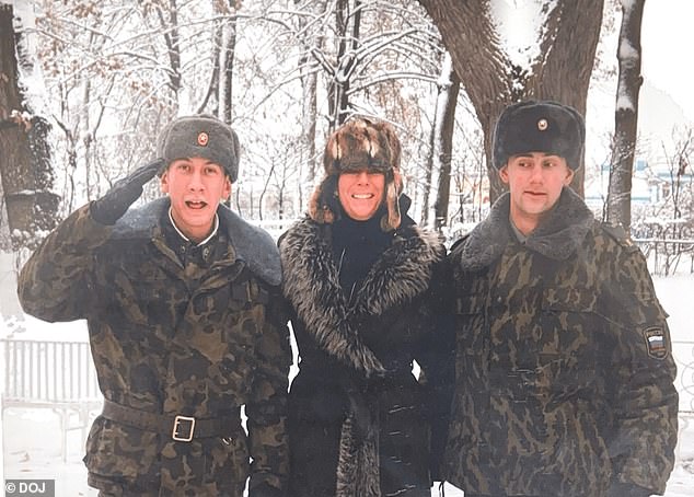 Ghislaine Maxwell smiles widely while appearing to be pictured between two Russian soldiers