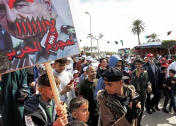 A youth hols up a sign at a protest in the coastal Libyan city of Tajura on Feb. 25, 2022.