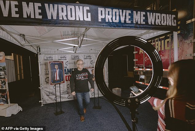 An attendee poses for portraits under a Prove me Wrong tent in the Exhibitor hall at Turning Point's annual AmericaFest conference,