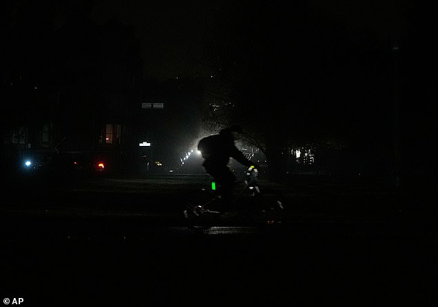 A bicyclist drives past head lights from an oncoming vehicle during the San Francisco power outage on Saturday