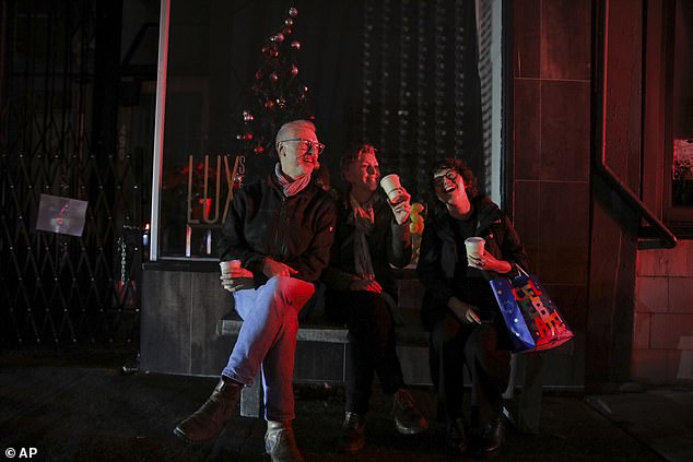 A trio sits on a bench in the darkness as they celebrate a birthday amid the major power outage in San Francisco