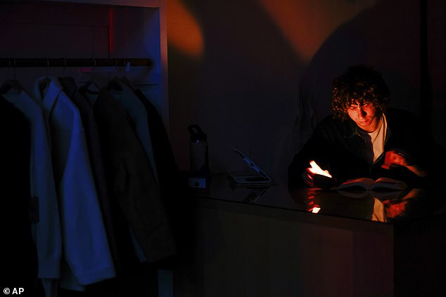 Miles Barrett, assistant designer at Industry of All Nations, reads Red Rising by Pierce Brown by candlelight during a power outage in San Francisco