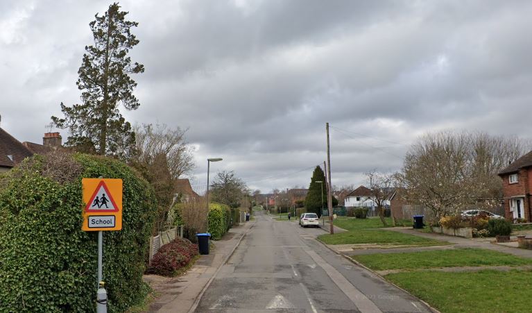 A residential street with a "School" sign featuring two children.