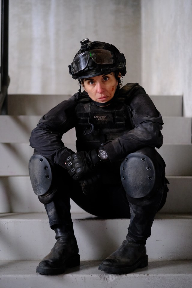 Vicky McClure as Lana Washington in the TV series "Trigger Point" sits on stairs, wearing a tactical helmet and vest.