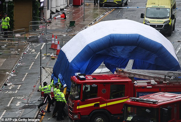 Police officers are seen covering an area with an inflatable tent to preserve evidence