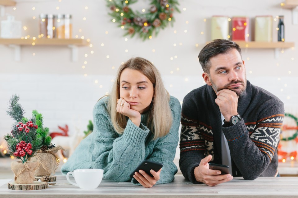 Young family couple quarreled over mobile phone and social networks, man and woman sad during the New Year holidays and Christmas