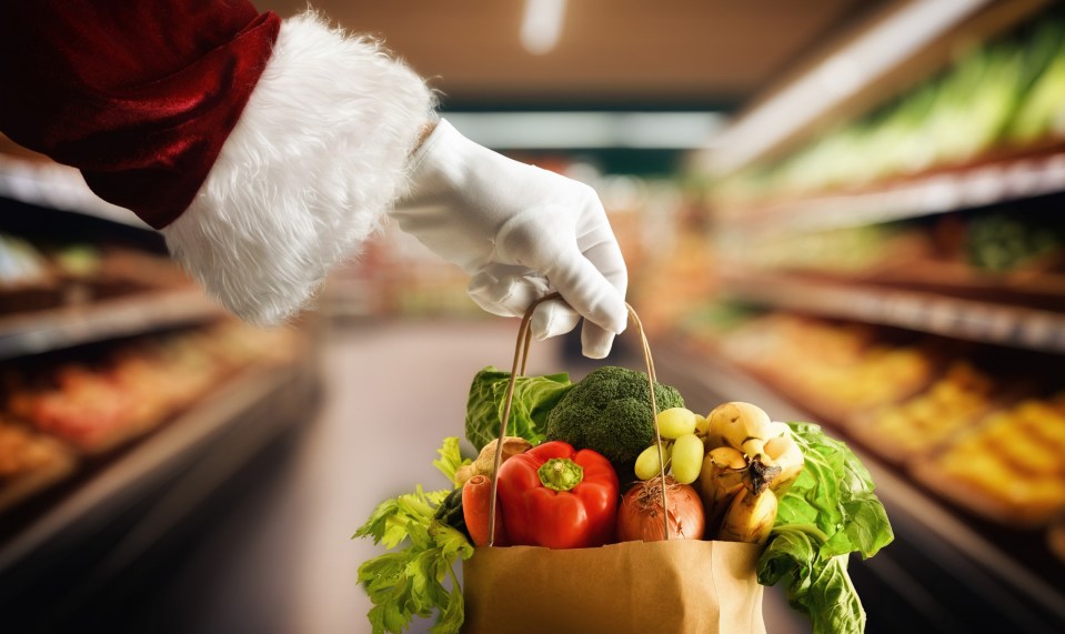 Santa's hand holding a bag of groceries in a supermarket.