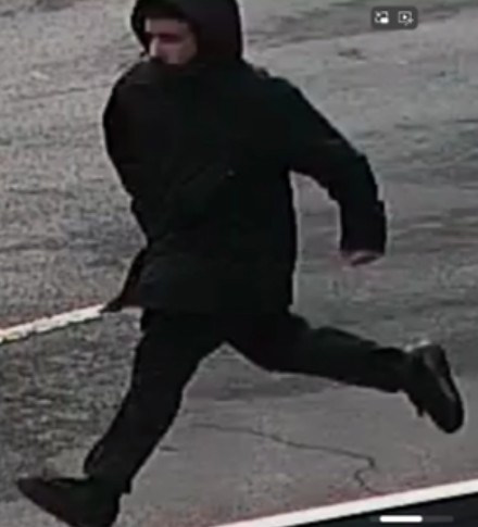CCTV image of a person in a dark hooded jacket and pants running.