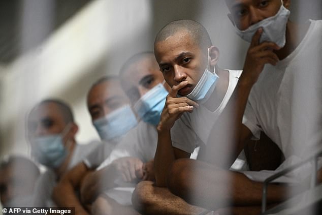 Inmates with blue face masks watch on in their cell inside the CECOT