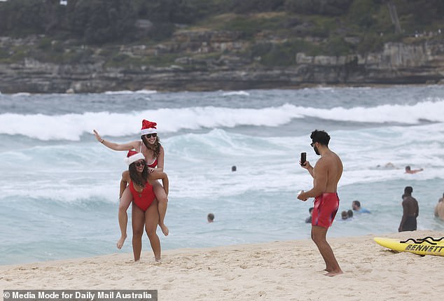 Friends wearing their Christmas-themed outfits piggy backed each other across the beach