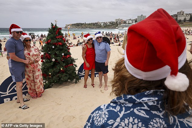 Loved ones huddled up close for photos in front of a Christmas tree on the beach