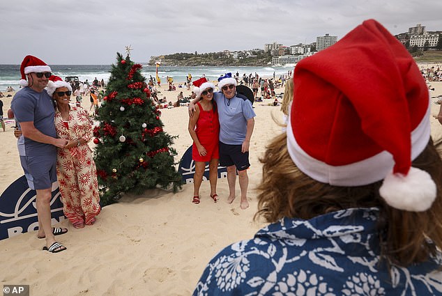 Chef Rami Tan, second right, dishes out tiramisu he made earlier to young women as they celebrate Christmas Day at Bondi Beach
